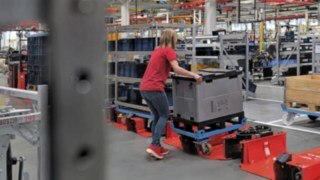 Una operaria carga un remolque de tren logístico con un carro de medio tamaño