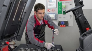 Empleado junto al panel de servicio de baterías Empleado junto al panel de servicio de baterías de Linde