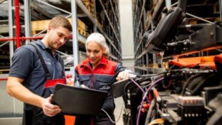 Dos técnicos de servicio de Linde Material Handling observan un ordenador portátil junto a un vehículo.