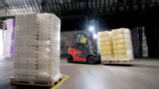 Carretilla elevadora de gas H20: la nueva generación Una carretilla elevadora H20 Linde con luz transporta carga en una nave con poca iluminación
