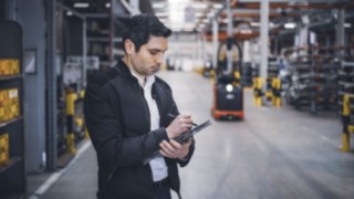 Un empleado de Linde Material Handling se encuentra en el almacén tomando notas en su tableta.