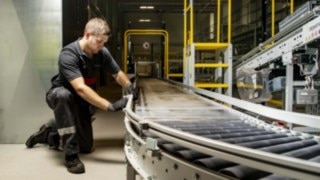 Un técnico de mantenimiento de Linde MH repara un transportador de rodillos