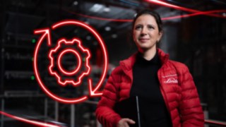 Una empleada de Linde Material Handling en un almacén, con el símbolo LED de una rueda dentada de color rojo al fondo.