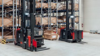 Dos carretillas de pasillo estrecho (VNA) de Linde MH con sistema de protección de personas integrado delante del almacén de pasillos estrechos