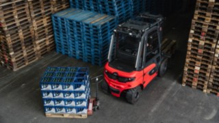 Los potentes sensores del Linde Reverse Assist Radar detectan de forma fiable objetos parados y en movimiento. La carretilla eléctrica Linde X30 sale marcha atrás de un pasillo en dirección a un obstáculo formado por cajas de bebidas.