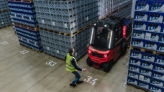El Linde Reverse Assist Radar reduce el riesgo de accidentes al dar marcha atrás. Una carretilla eléctrica de Linde sale marcha atrás de un pasillo mientras pasa un peatón.