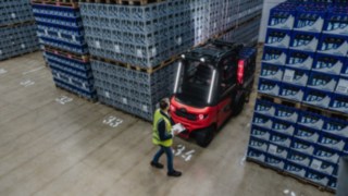 La carretilla eléctrica Linde X30 sale marcha atrás de un pasillo, con un peatón en la zona trasera.
