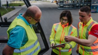 Tres personas con chalecos reflectantes conversando: Asesoramiento en seguridad in situ en las instalaciones del cliente. Tres personas con chalecos reflectantes conversando: Asesoramiento en seguridad in situ en las instalaciones del cliente.
