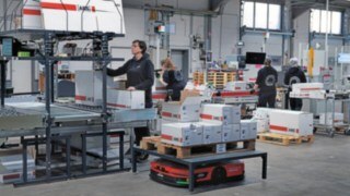 Vehículo de plataforma automatizado C-MATIC de Linde MH rodeado de un grupo de empleadas del almacén de ABS Safety.