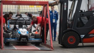 Una carretilla de alquiler de Linde eleva un coche de carreras mediante un dispositivo especial durante el evento de Fórmula Student en el circuito de Hockenheim Una carretilla de alquiler de Linde eleva un coche de carreras mediante un dispositivo especial