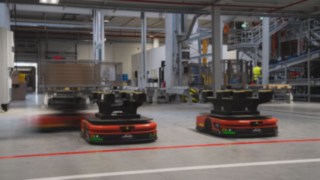 Tres robots móviles autónomos (AMR) de Linde MH circulan por el almacén