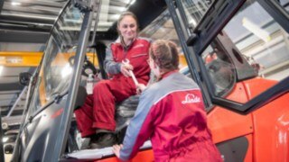 Nuestros empleados desempeñan un papel fundamental en nuestra política de sostenibilidad. Una técnica de mantenimiento entrega una herramienta a otra técnica de mantenimiento en la carretilla elevadora.
