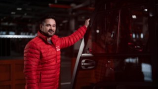 Un empleado de Linde Material Handling está de pie junto a un vehículo de manutención y sonríe a la cámara.