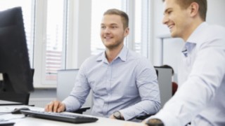 Conversación entre empleados de Linde ante el escritorio con ordenador Conversación entre empleados de Linde ante el escritorio con ordenador