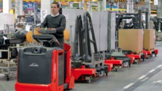 Trenes logísticos de Linde en naves de producción Conductor sobre un tren logístico de Linde en un almacén
