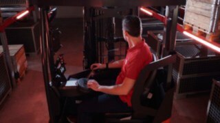 El conductor se sienta en la cabina ergonómica de la carretilla retráctil Ri16 de Linde MH.