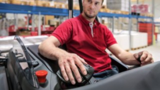 El reposabrazos permite ejecutar todos los movimientos de control desde la muñeca, sin esfuerzo innecesario del antebrazo. Un empleado coloca la mano sobre el joystick multifunción de Linde Material Handling