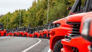 Muchas carretillas elevadoras de Linde Material Handling alineadas en un aparcamiento.