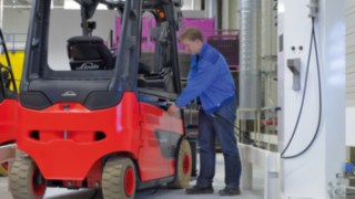 El uso de propulsiones de Litio-Ion posibilita la carga intermedia periódica de las carretillas. Un empleado carga una carretilla elevadora de Linde Material Handling